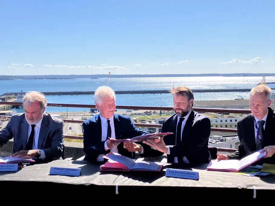 Des hommes signent un document officiel sur le parvis de la gare de Brest, au-dessus du port