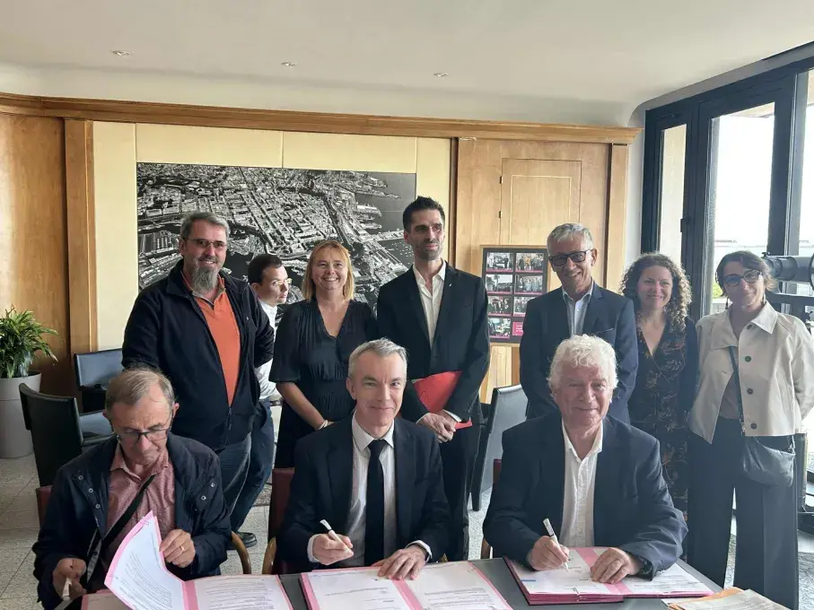 3 hommes derrière un bureau signent un partenariat.
