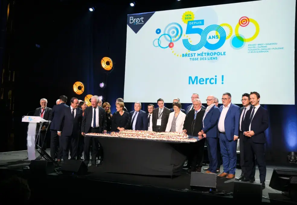Plusieurs personnes sont sur scène devant un écran géant