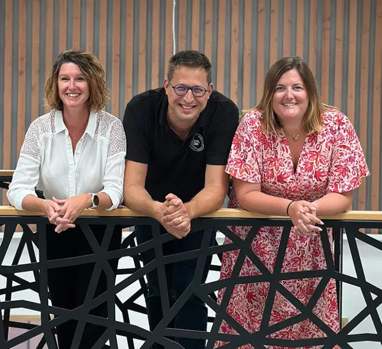 Trois personnes de face, accoudée à un garde corps