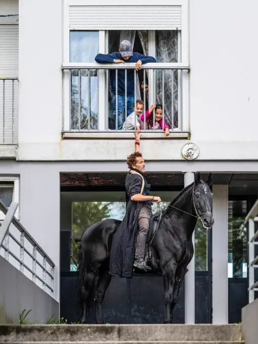 Un homme a cheval donnant la main à un enfant sur un balcon