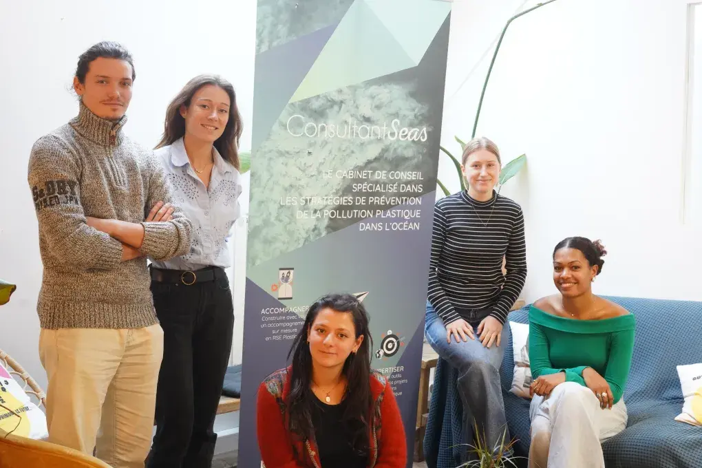 quatre femmes et un homme posent devant une affiche