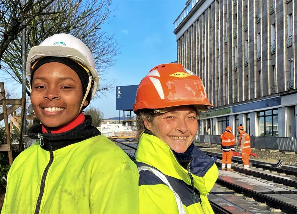Deux femmes en chasuble de chantier posant dos à dos