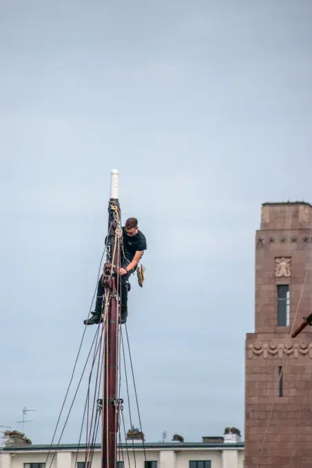 Une personne en haut d'un mât qui le répare