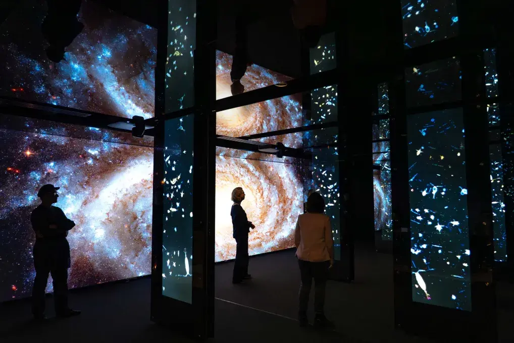 Une silhouette dans une salle plongée dans le noir avec des projections au mur