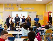 Cinq personnes debout devant le tableau du salle de classe.