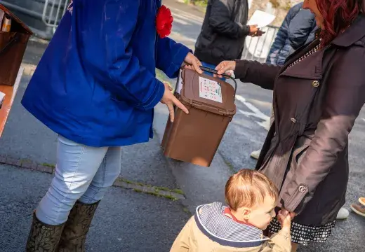 Deux personnes échangent un seau de déchets.
