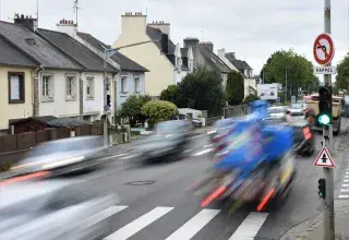 Des voitures passent à grande vitesse à côté d'habitations. 